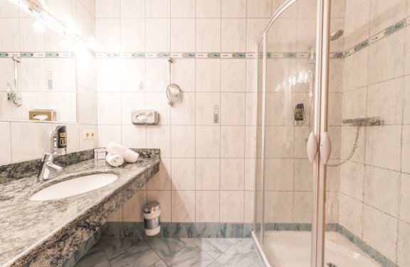 Helles Bad mit Granitwaschtisch, großer Dusche und Wandspiegel