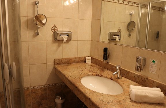 Badezimmer mit Marmorwaschbecken, Handtuch, Seifenspender und Spiegelwand