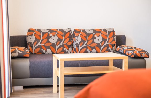 Sofa mit floralen Polstern in Orange, Grau und Schwarz