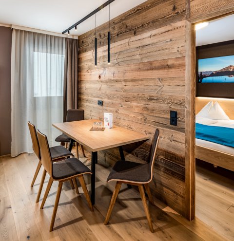 Wohnbereich mit Holzwand, Esstisch und Blick ins Schlafzimmer