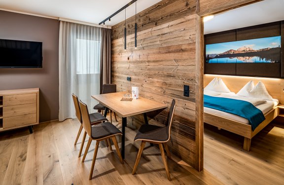 Wohnbereich mit Holzwand, Esstisch und Blick ins Schlafzimmer