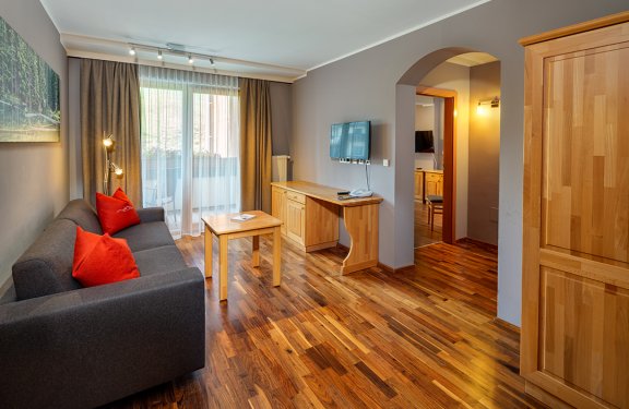 Wohnbereich mit Sofa, TV und Zugang zum Balkon