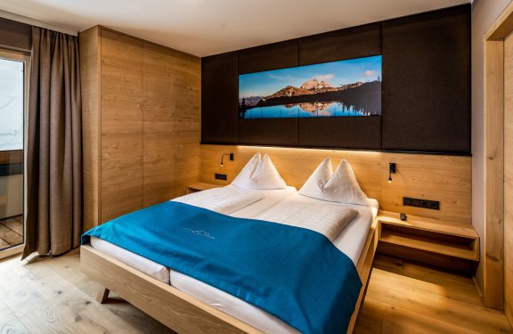 Schlafzimmer mit Holzmöbeln, Doppelbett und Bergbild über dem Bett