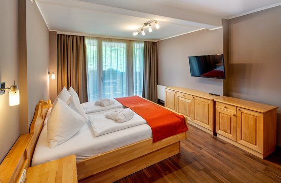 Schlafzimmer mit Doppelbett, rotem Läufer und Flachbildfernseher