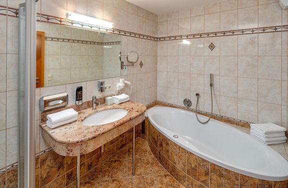 Badezimmer mit Marmorboden, großer Badewanne und Spiegelwand