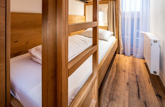 Stockbett mit Holzrahmen in schmalem, lichtdurchflutetem Raum