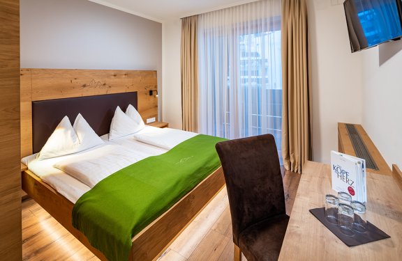 Doppelbett mit grünem Läufer in modernem Zimmer mit Schreibtisch