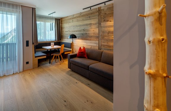 Wohnbereich mit Holzwand, Sofa und Essecke am Fenster
