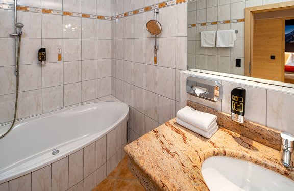 Badezimmer mit Eckbadewanne und Waschbecken aus Naturstein