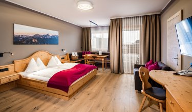 Spacious double room with wooden furniture and red bed throw