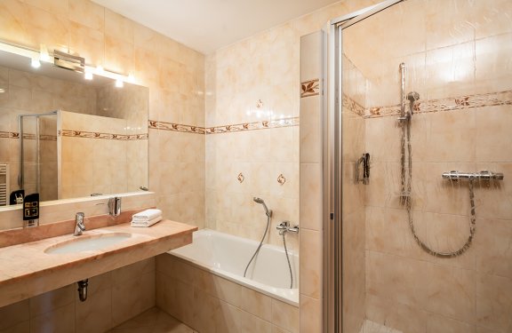 Klassisches Bad mit Dusche, Badewanne und großem Spiegel