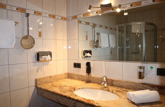 Helles Badezimmer mit Marmorwaschbecken, Handtüchern und großem Spiegel an der Wand