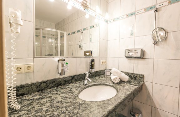 Badezimmer mit grauer Marmorarbeitsplatte, Waschbecken, Spiegel und Handtüchern