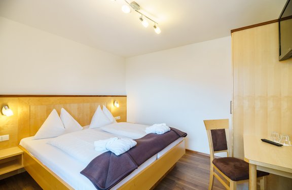 Doppelbett mit brauner Decke und heller Holzmöblierung