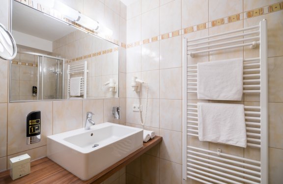 Badezimmer mit Handtuchtrockner, Waschbecken und großem Spiegel