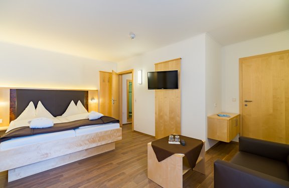 Doppelzimmer mit Sofa, Couchtisch und Flachbildfernseher