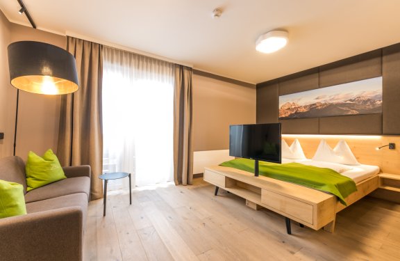 Gemütliches Zimmer mit Doppelbett, Sofa, TV und großem Fenster