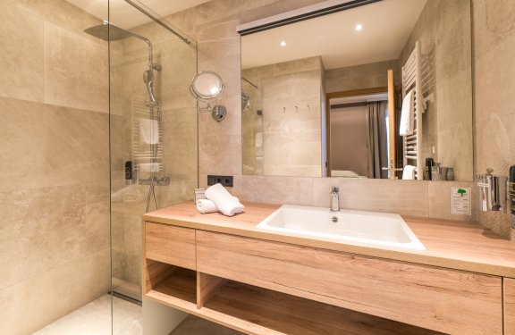 Modernes Bad mit großer Dusche, Holzwaschtisch und großem Spiegel