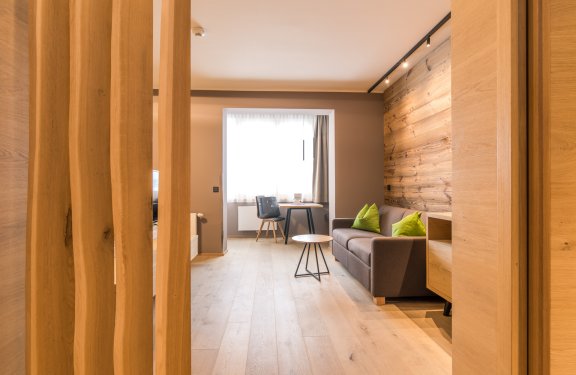 Heller Wohnbereich mit Holzboden, Sofa und Schreibtisch am Fenster
